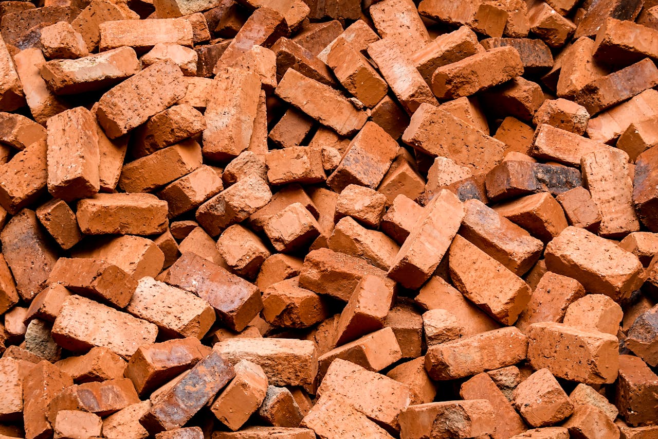 High-quality close-up image of a large pile of red clay bricks, ideal for construction projects.